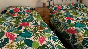A bedroom with two single beds, a nightstand, a lamp, a mirror, and a wall clock. - Peaceful Ocean facing Island Escape (Kawau Island)