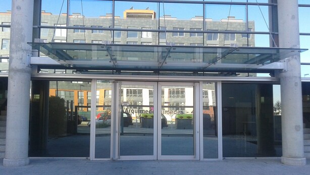 A modern building entrance with glass doors and a glass roof. - Studio 15 km from the center of Madrid (Leganés)