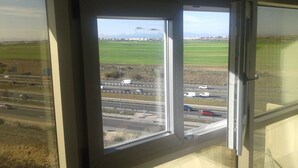 A view through a window of a highway with multiple lanes, vehicles, and a green field in the distance. - Studio 15 km from the center of Madrid (Leganés)