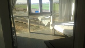 A bedroom with a large window overlooking a highway and fields. - Studio 15 km from the center of Madrid (Leganés)