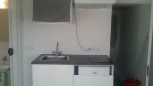 A compact kitchen with a sink, a small countertop, and a built-in dishwasher. - Studio 15 km from the center of Madrid (Leganés)