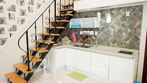 A kitchen with a black spiral staircase, white cabinets, and a tiled backsplash. - Ulsan Edelweiss Pension (Ulsan)