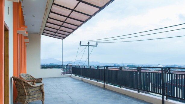 Ein Balkon mit Korbstuhl, Blick auf die Stadt und Metallgeländer.