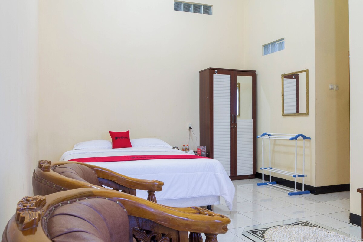 A hotel room with a bed, a wardrobe, a mirror, and a shoe rack.