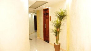 Un pasillo con una planta en maceta, una puerta de madera y un piso de color claro.