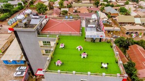 Un edificio de gran altura con terraza en la azotea, que cuenta con un césped y varias mesas.