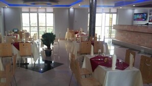 Un restaurante con varias mesas, sillas y una planta en maceta en el centro.