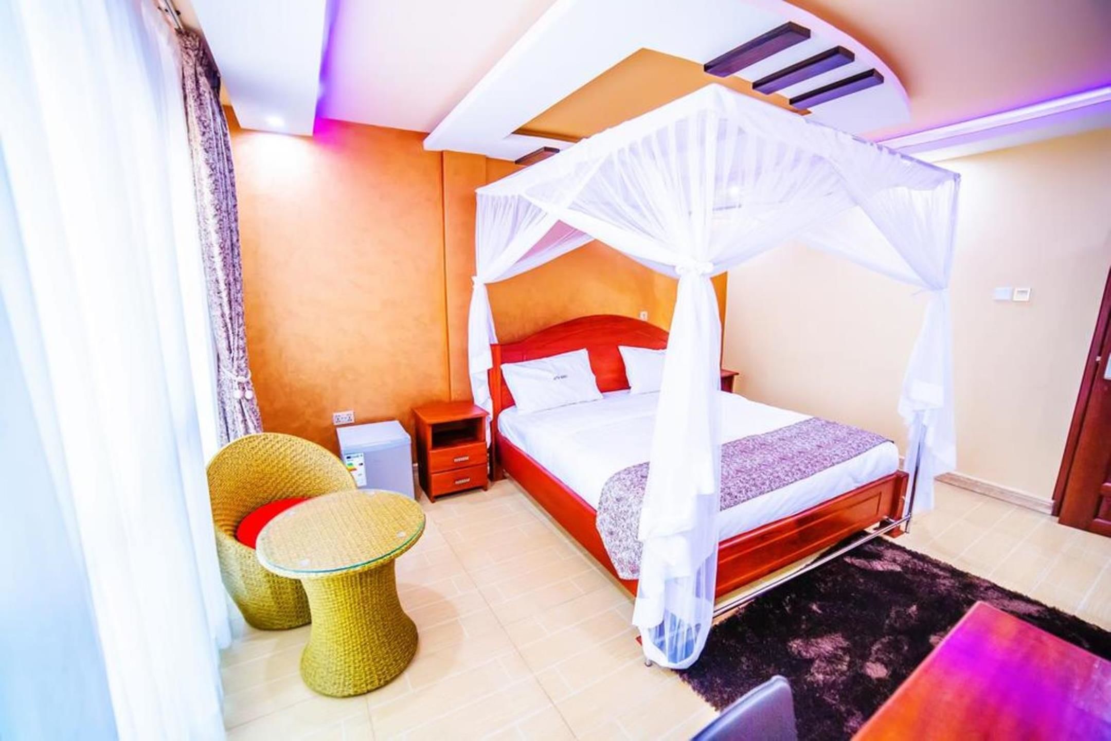 A bedroom with a four-poster bed, a small table, and a chair.