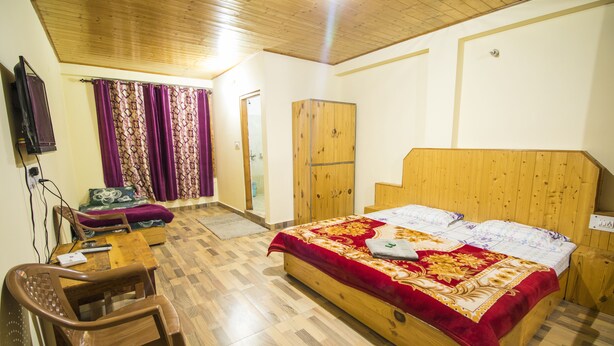 A bedroom with a wooden bed, a wooden wardrobe, a wooden desk, and a chair. - Paradise Guest House (Manali)