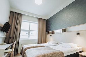 A hotel room with two beds, a desk, a chair, a television, and a window with curtains. - Viiking Spa Hotel (Parnu)