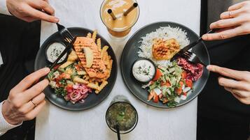 Una mesa con dos platos de comida, un vaso de bebida helada y un recipiente pequeño con salsa.