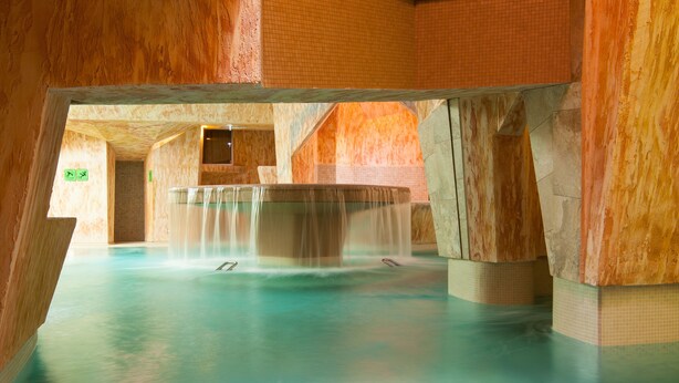 A large indoor pool with multiple water features and a stone wall design. - Viiking Spa Hotel (Parnu)