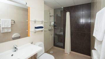 Un baño moderno con lavabo blanco, inodoro y ducha con mampara de vidrio.