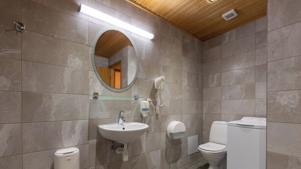 A bathroom with a sink, mirror, toilet, and a washing machine. - Viiking Spa Hotel (Parnu)