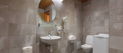 Un baño con lavamanos, espejo, inodoro y lavadora.