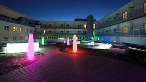 A courtyard with modern architecture, a wooden deck, and illuminated sculptures. - Viiking Spa Hotel (Parnu)