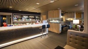 A modern bar area with a counter, bar stools, and a variety of bottles. - Viiking Spa Hotel (Parnu)