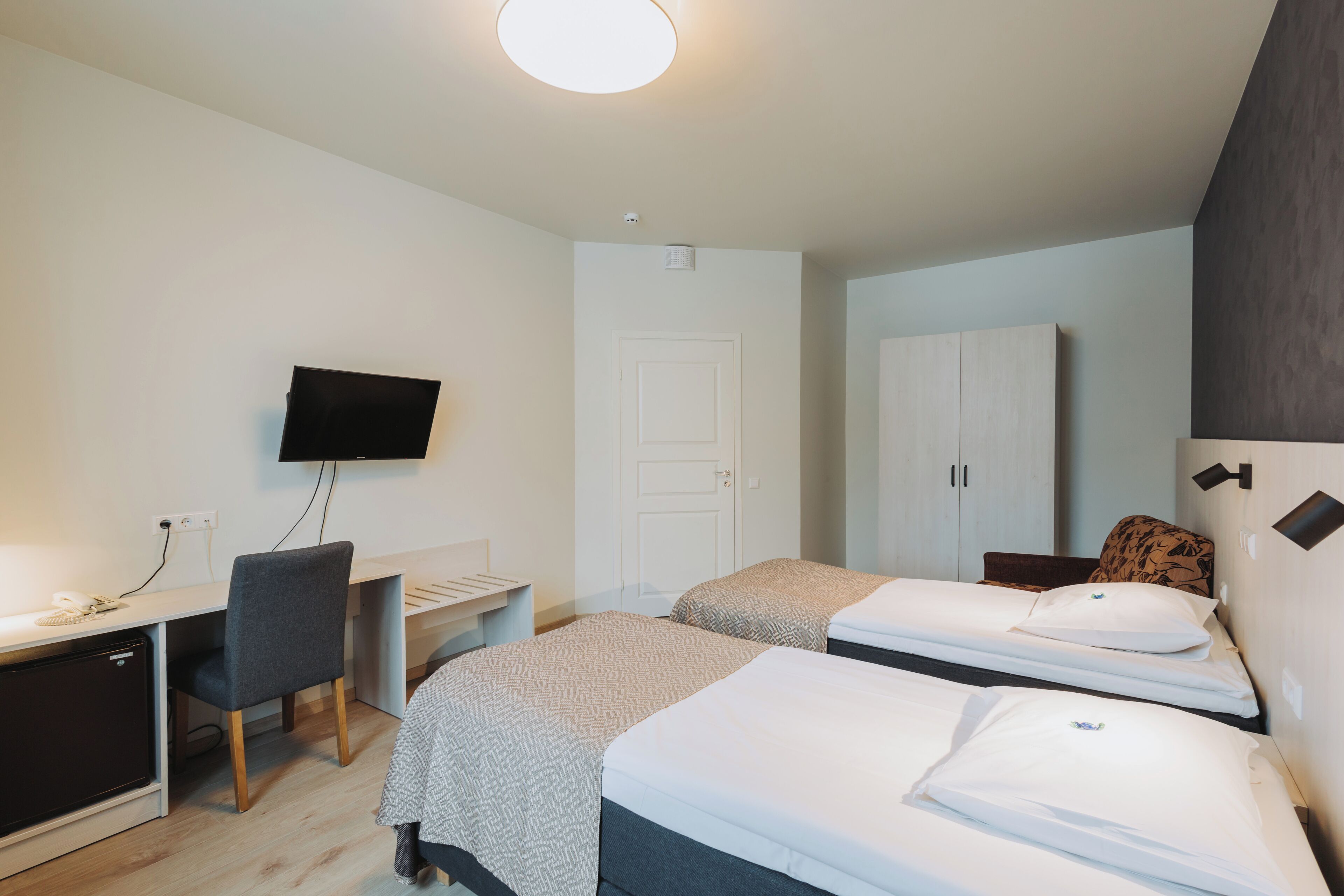 Una habitación de hotel con dos camas, un escritorio, un televisor y un armario.