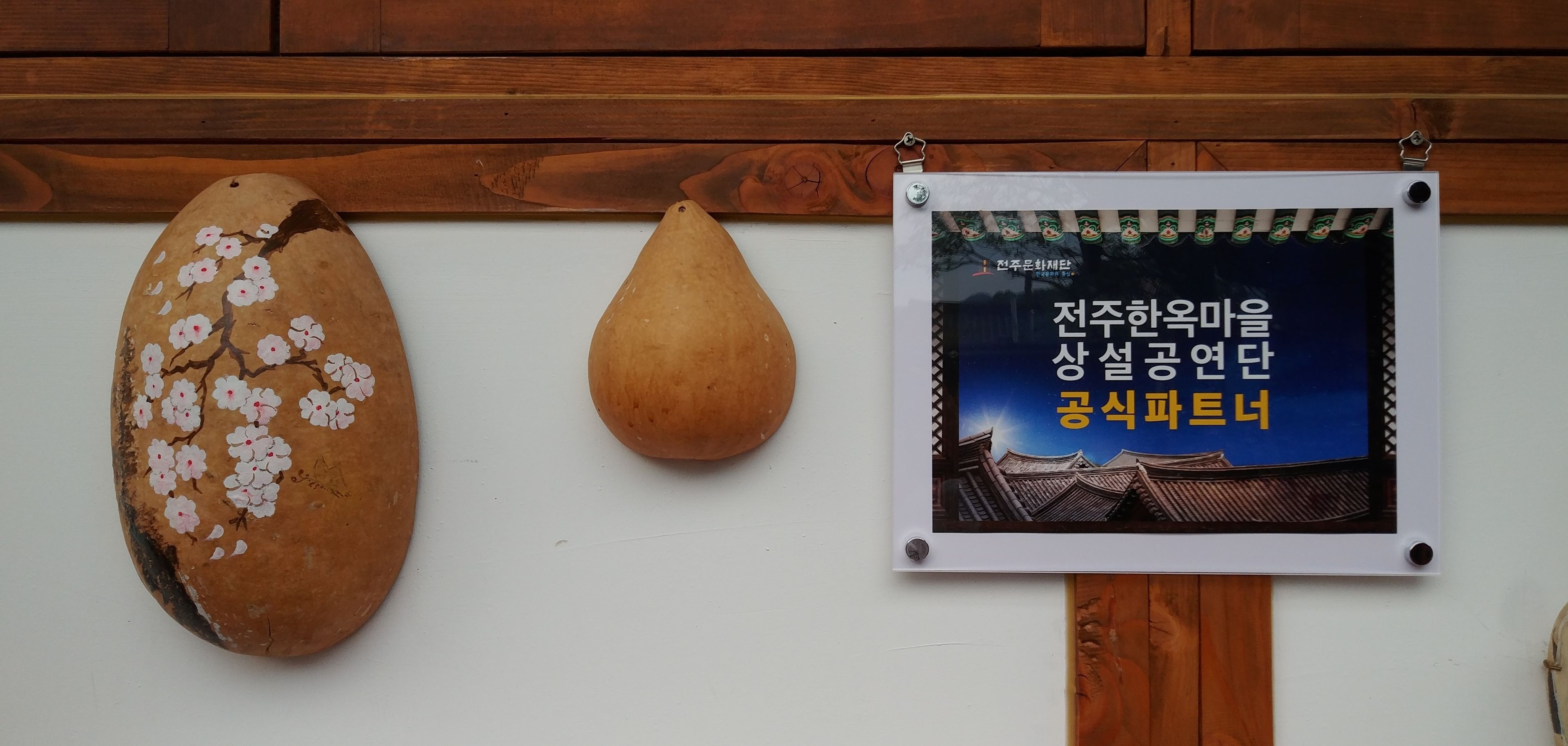 Twee houten sculpturen en een lijst met een bord op een muur.