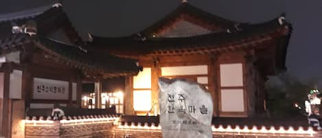 A traditional Korean building with a stone monument in front.