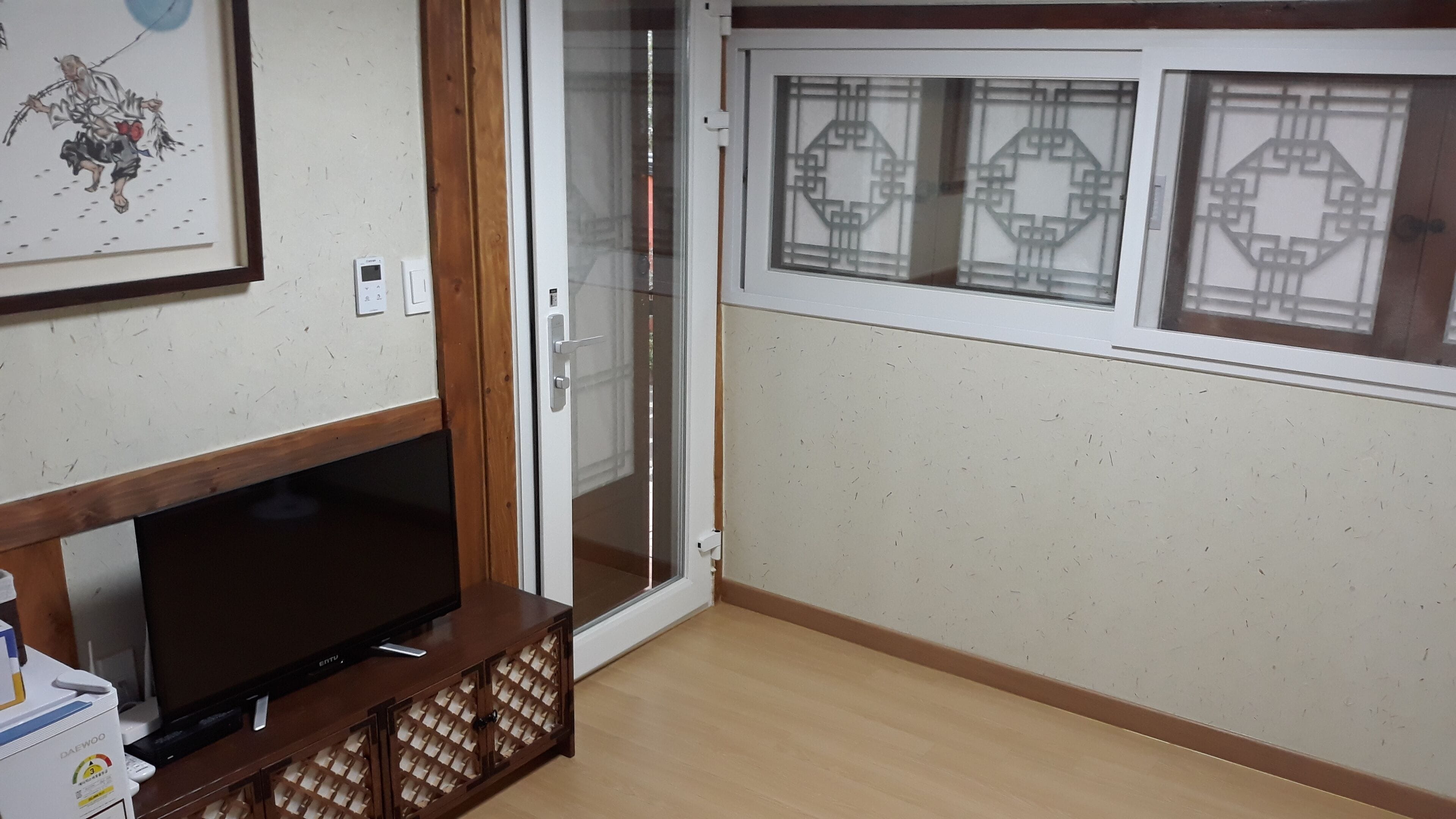 A room with a wooden entertainment unit, a sliding glass door, and a wall with decorative window grills.