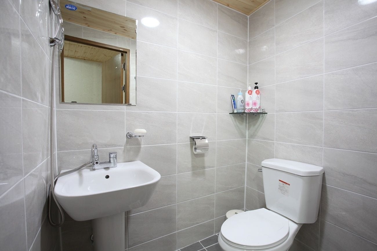 A bathroom with a white sink, toilet, and mirror.