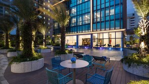 A modern hotel courtyard with outdoor seating, palm trees, and a pool area. - Citadines Balestier Singapore (Singapore)