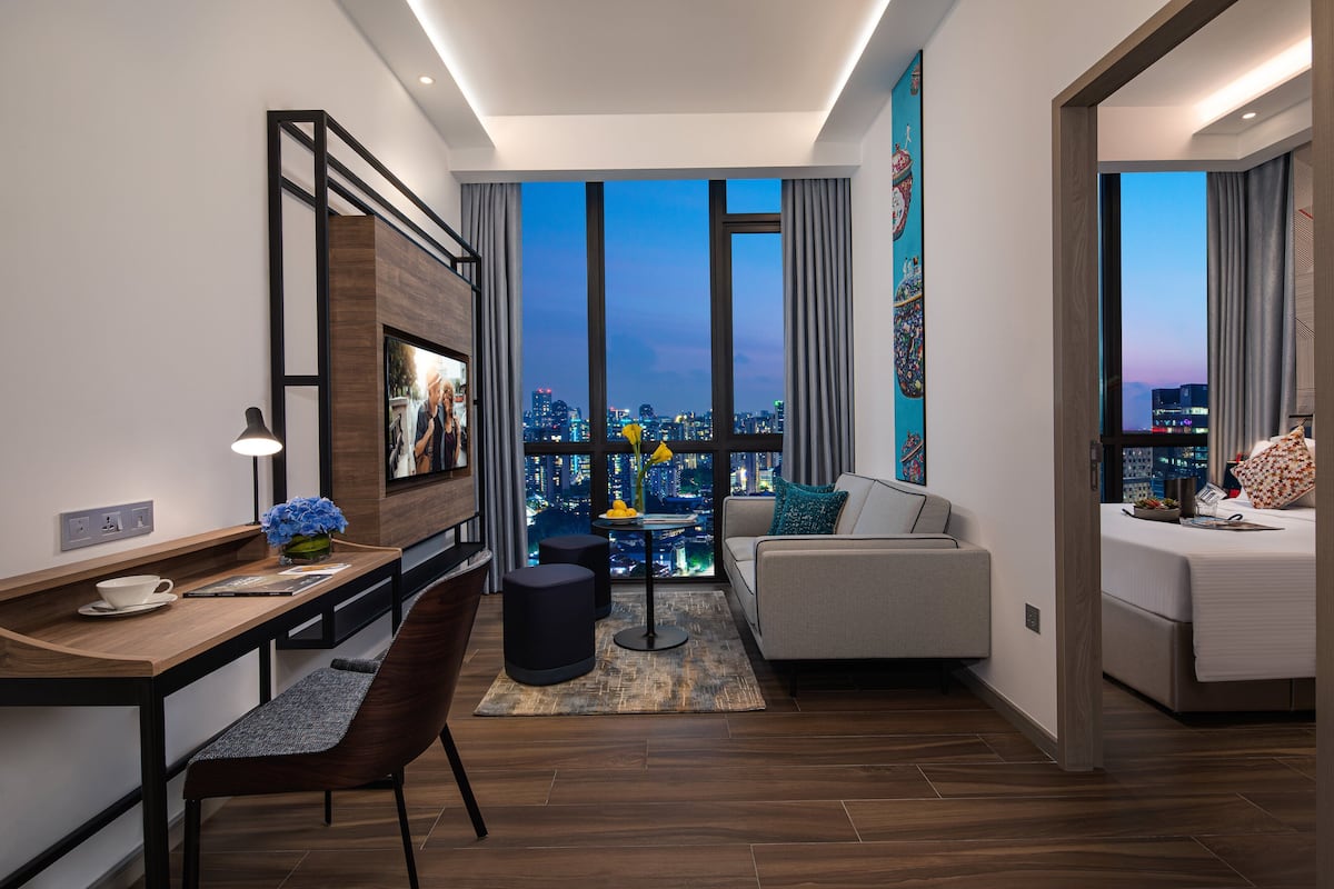 Una habitación de hotel moderna con vista a la ciudad, un área de comedor y un rincón de estar acogedor.