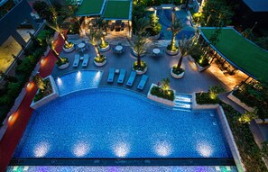 Vista aérea de un hotel con una piscina grande, zonas de estar al aire libre y jardines ajardinados.