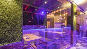 A modern restaurant with a glass partition, wooden tables, and a green wall. - The Siddhartha (Dharamshala)