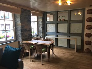 A room with a wooden table, wicker chairs, a blue accent wall, and a view through a window. - Vacation apartment D, Prinz-Karl-Str., outskirts - Edition Bad Wimpfen (Bad Wimpfen)