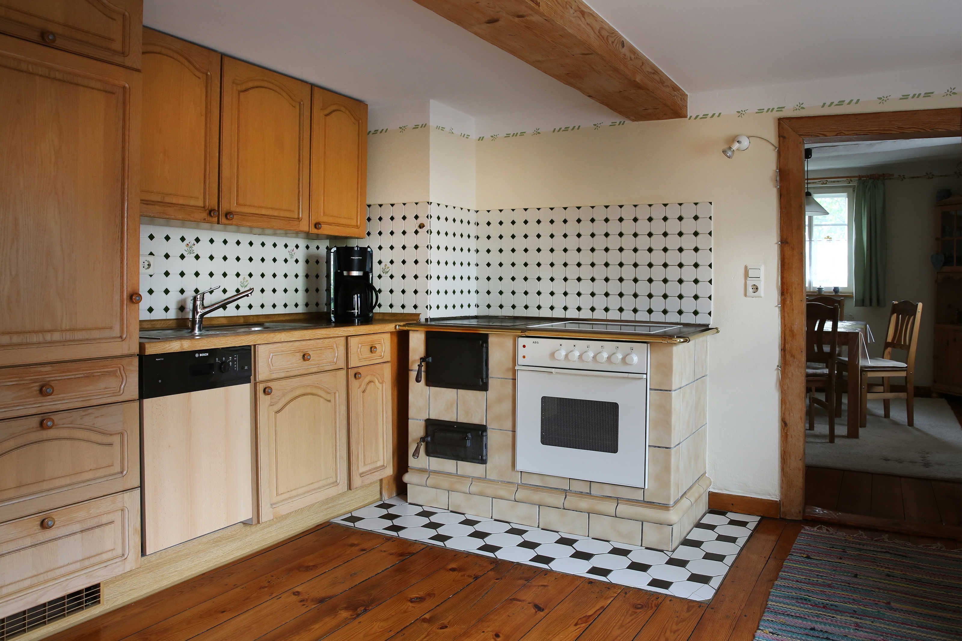 A kitchen with wooden cabinets, a dishwasher, a coffee maker, and a vintage oven.