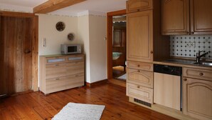 Una cucina con mobili in legno, una lavastoviglie Bosch e un forno a microonde sul piano di lavoro.