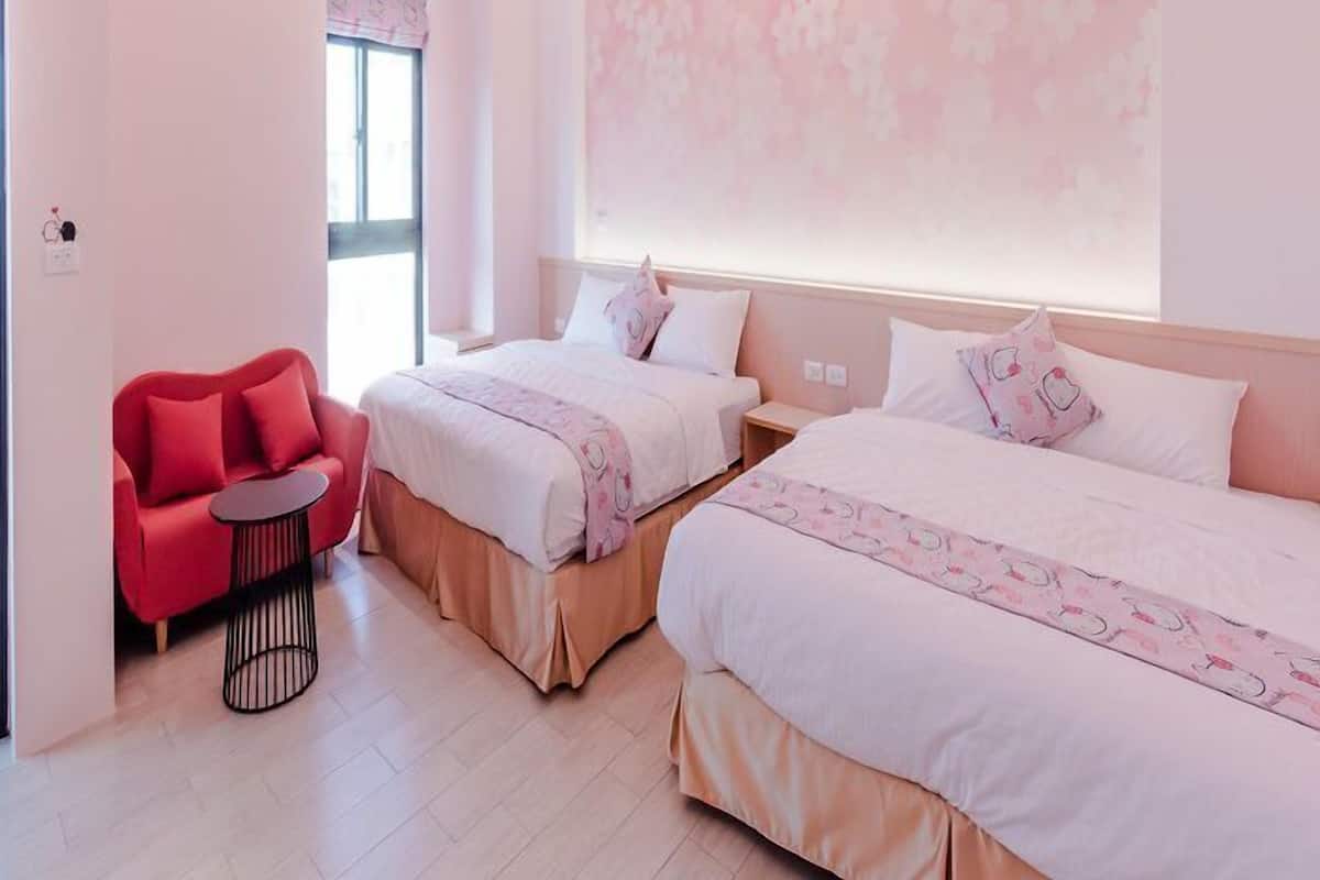 A hotel room with two beds, a red chair, and a large floral wall.