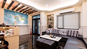 A modern living room with a sofa, coffee table, and a map mural on the wall. - Tiamo B&B (Magong)