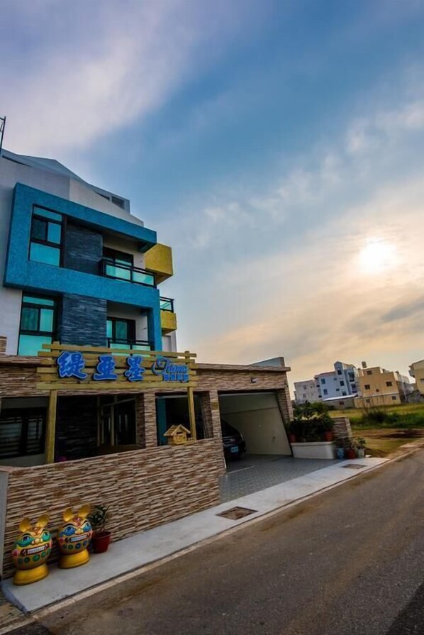 Un bâtiment moderne à la façade bleue, avec un garage apparent et un ciel dégagé.
