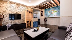 A modern hotel lobby with a curved ceiling, a reception desk, a flat-screen TV, and a seating area with a coffee table. - Tiamo B&B (Magong)