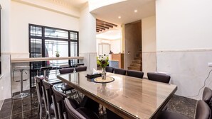 A modern dining area with a long wooden table, black chairs, and a vase of flowers. - Tiamo B&B (Magong)