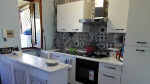 Une cuisine avec des meubles blancs, un pare-feu en carrelage, une cuisinière à gaz et un lave-vaisselle.