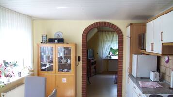 A kitchen with a dining area, a brick archway, and a view of the garden.