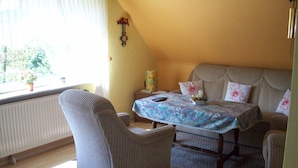 Una habitación acogedora con cama, una silla, una mesa y ventana con vistas a la vegetación.
