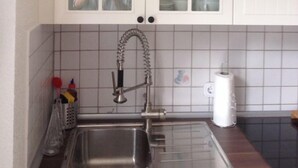 A kitchen with white cabinets, a stainless steel sink, and a tiled backsplash. - listed family home, close to Gottorf Castle  (Schleswig)