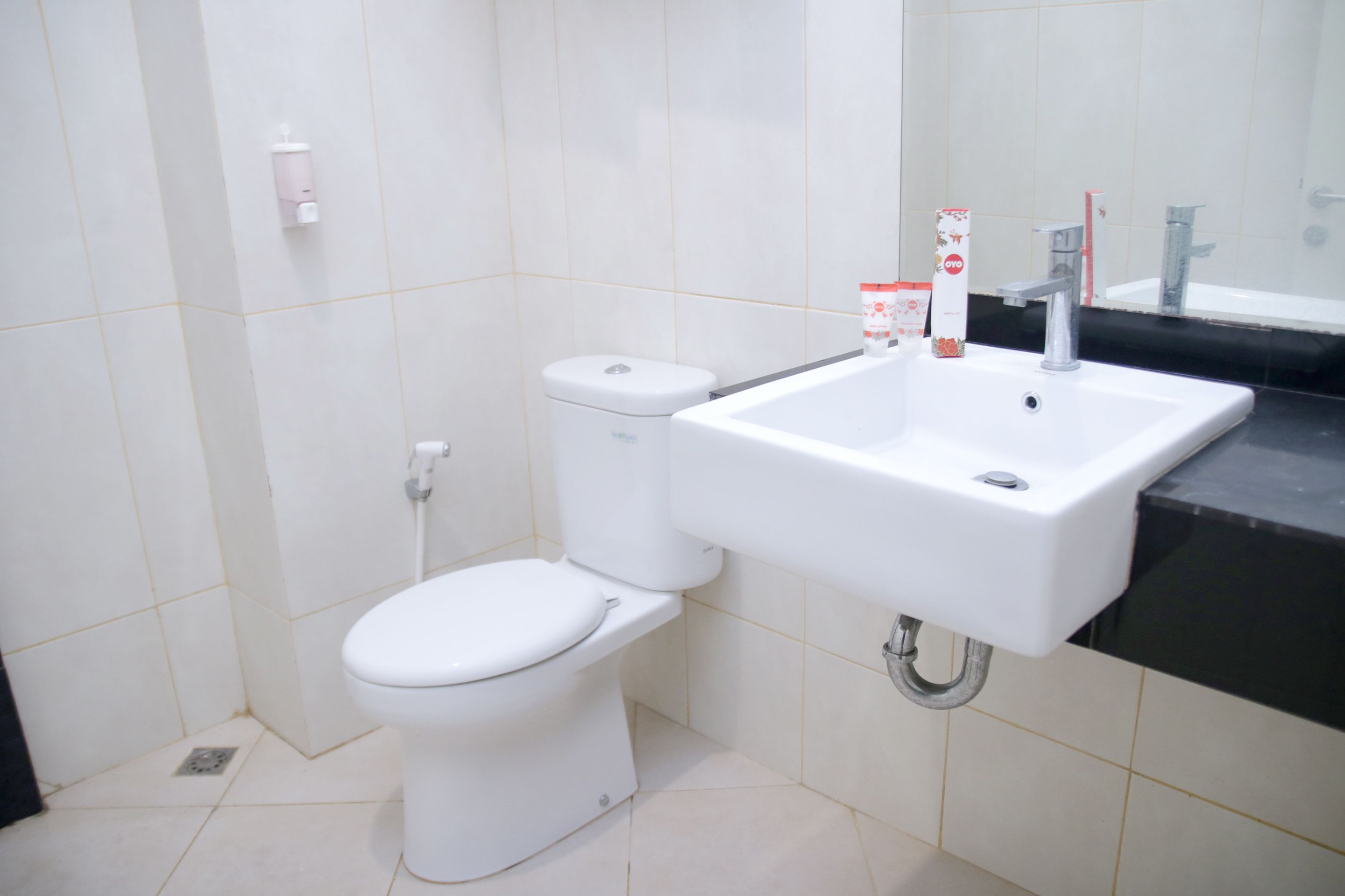 Un baño moderno con inodoro blanco, lavabo y espejo.