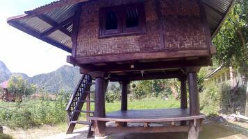 A rustic wooden house with a sloped roof, a small window, and a wooden staircase leading to a platform.