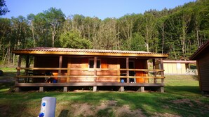 Una cabaña de madera con porche, rodeada de bosque.