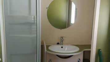 A bathroom with a shower, sink, and mirror.