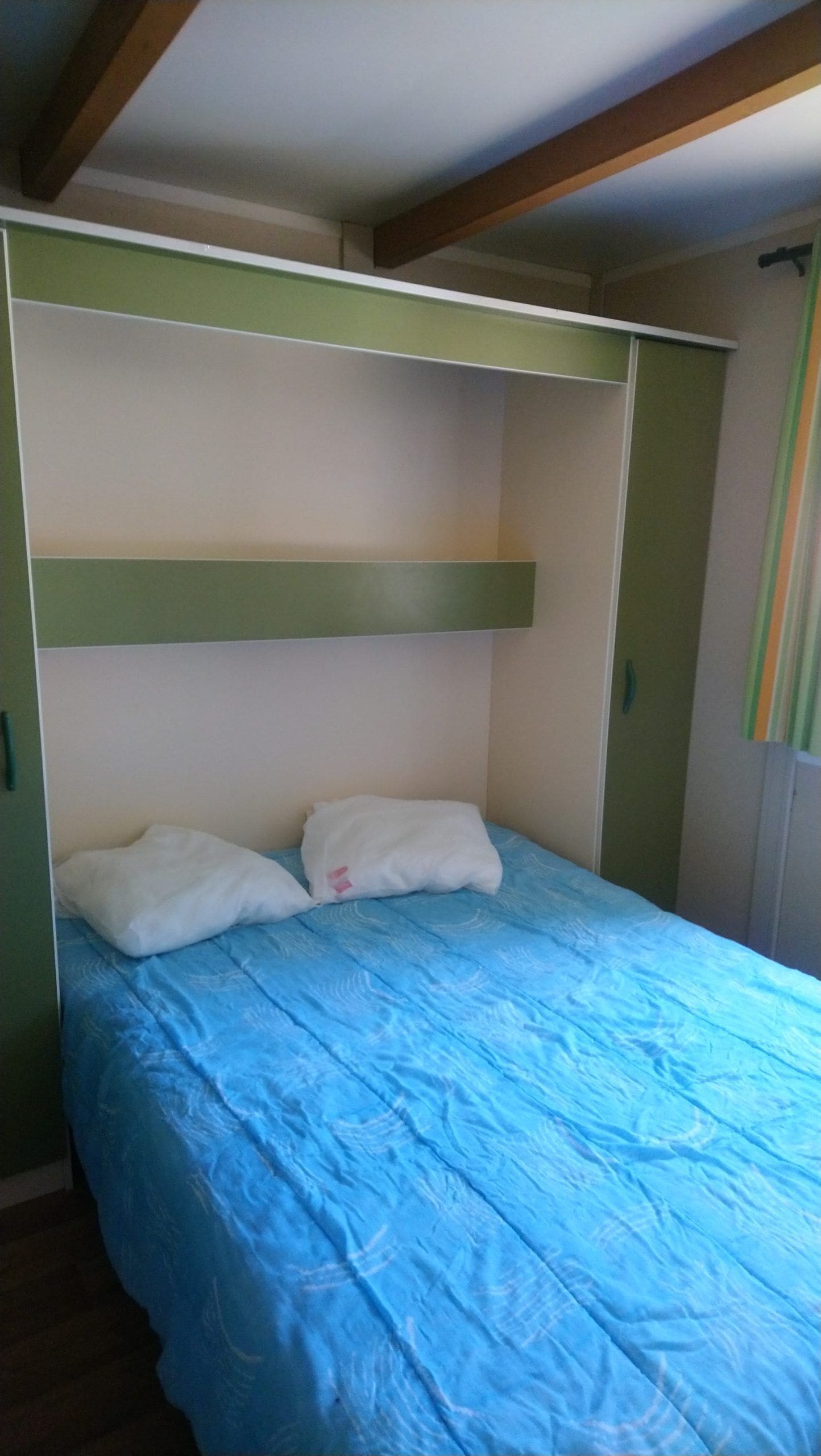 Una habitación con literas, una colcha azul y paredes verdes.