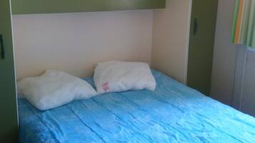 Una habitación con literas, una colcha azul y paredes verdes.