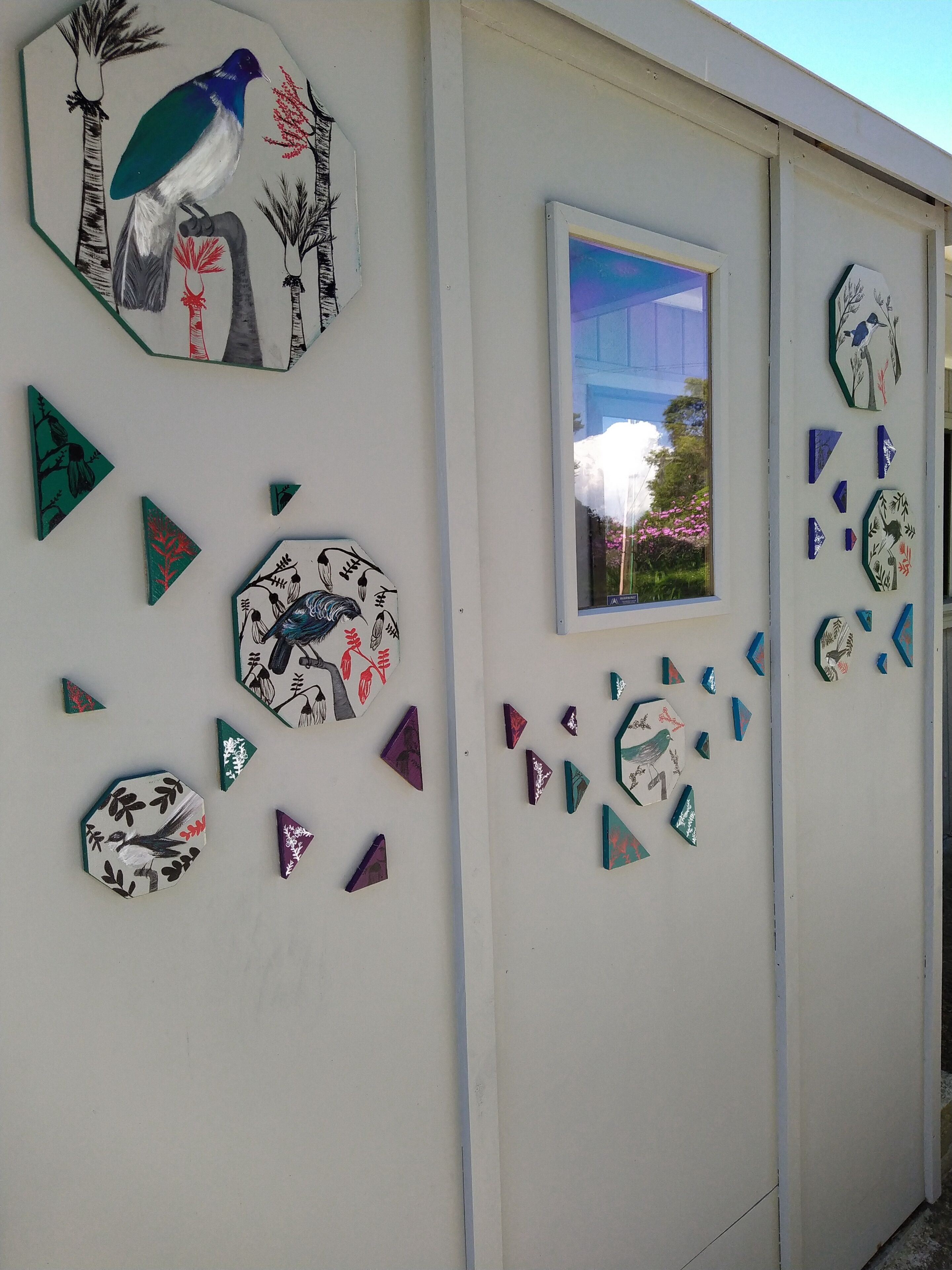 Een muur met verschillende geometrische en vogel-achtige decoraties.