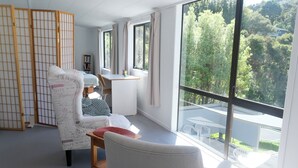 Habitació amb una finestra gran, un separador de fusta, una taula i una cadira.